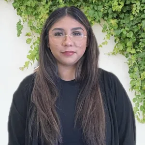 stacey is standing in front of a white wall with green vines